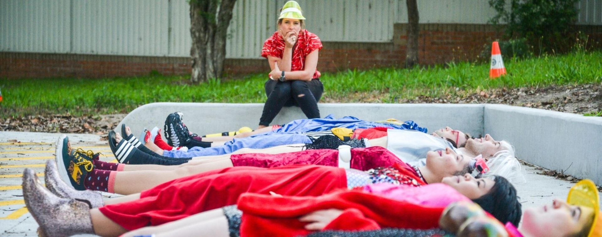 WE ARE HERE Company members lying on the ground outdoors